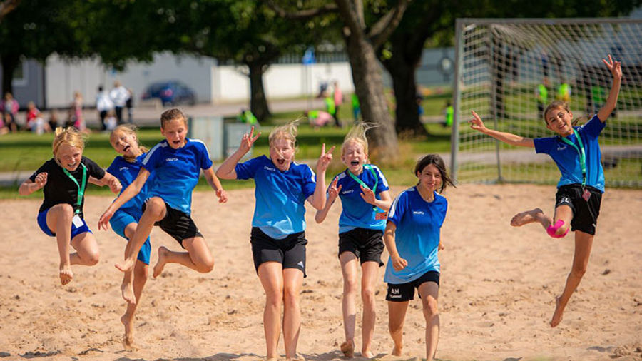 Barn i sportkläder som hoppar i sand.