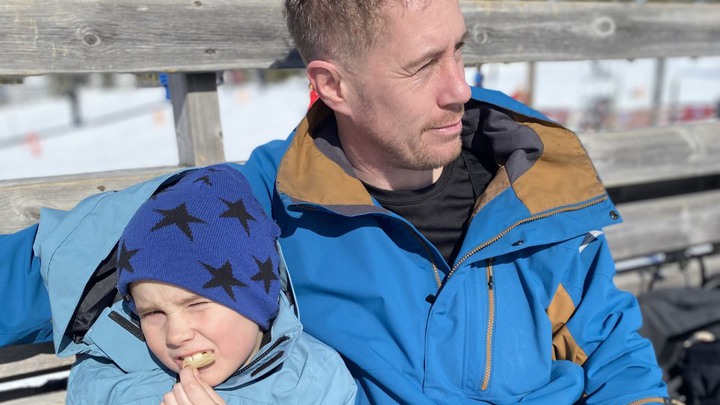 Karl och Joakim sitter ute p&aring; en b&auml;nk en solig vinterdag. Karl &auml;ter chips.