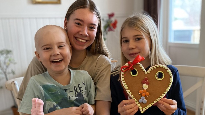 Karl sitter i sin syster Elsas kn&auml;, med Signe bredvid. Signe h&aring;ller i ett stort pepparkakshj&auml;rta.