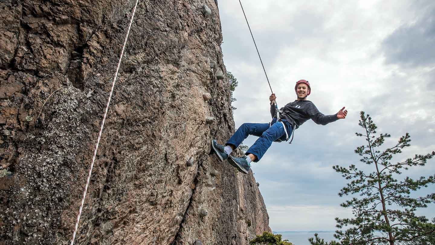 Pojke klättrar på bergsvägg
